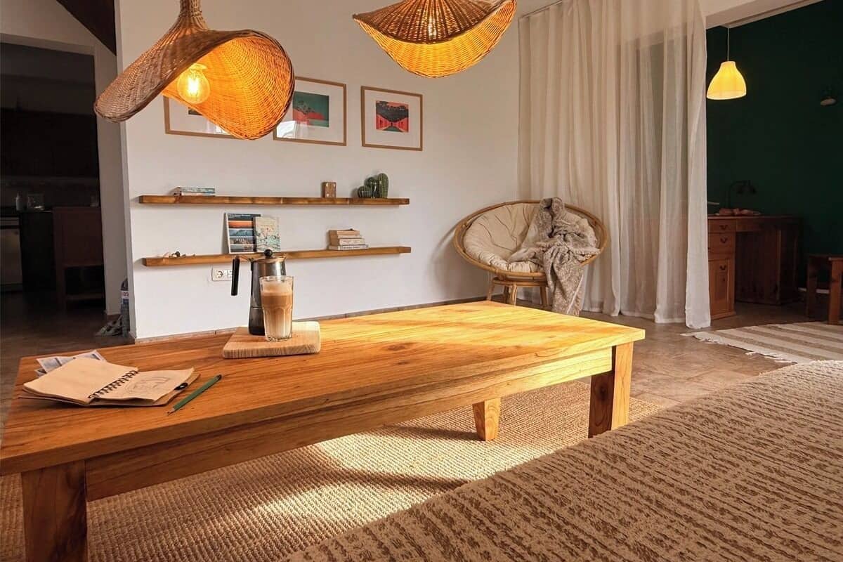 A cozy living room with a wooden coffee table, wicker pendant lights, and a rattan chair.