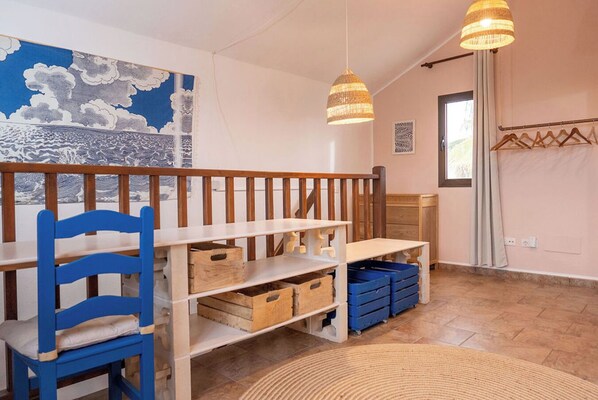 Ein Spielbereich für Kinder mit blauem Stuhl, Holzregalen und Aufbewahrungsboxen.