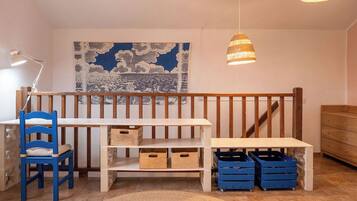 A room with a wooden bench, a blue chair, a white desk, and a wall with a cloud-patterned tapestry.