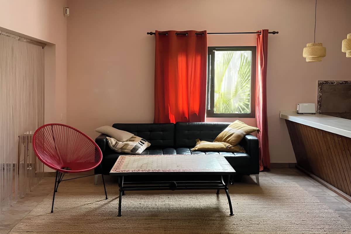 A living room with a black sofa, red chair, and a small table.