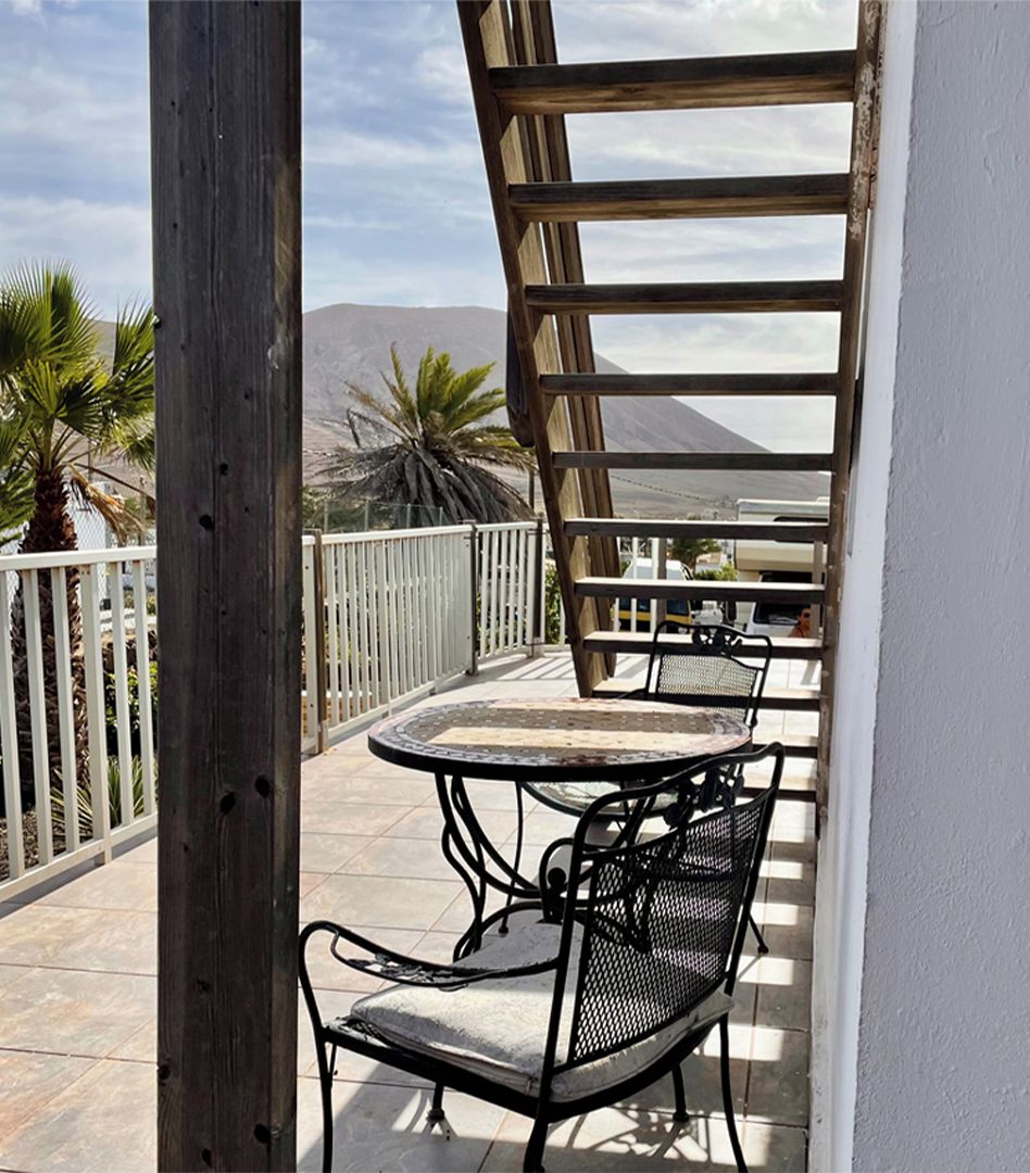 Ein Balkon mit Tisch und Stühlen, einer Holz-Pergola und Blick auf einen Berg.