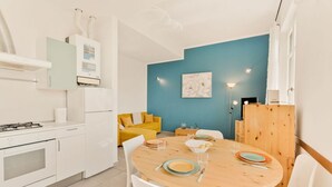 Et moderne køkken med hvide hårde hvidevarer, et spisebord med stole og en blå væg.