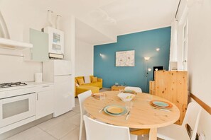 A modern kitchen with white appliances, a dining table with chairs, and a blue accent wall. - [La Conchiglia] 5Terre-Best position-Sea view (Corniglia)