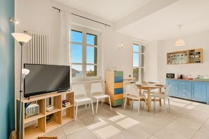 A modern living room with a flat-screen TV, white chairs, a wooden cabinet, and a dining table. - [La Conchiglia] 5Terre-Best position-Sea view (Corniglia)