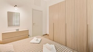 A bedroom with a bed, a dresser, a wardrobe, and a mirror.