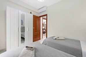 Une chambre avec deux lits, une armoire et un appareil de climatisation.