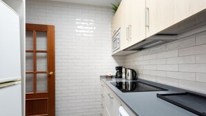 A kitchen with white tiled walls, wooden cabinets, a black countertop, and a built-in oven. - 'Apartamento Mariblanca 6' with Balcony, Wi-Fi and Air Conditioning (Málaga)