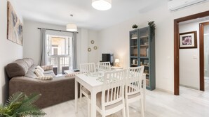 A modern living room with a sofa, dining table, chairs, and a TV. - 'Apartamento Mariblanca 6' with Balcony, Wi-Fi and Air Conditioning (Málaga)