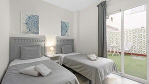 A hotel room with two beds, a nightstand with a lamp, and a sliding glass door to an outdoor area. - 'Apartamento Mariblanca 6' with Balcony, Wi-Fi and Air Conditioning (Málaga)