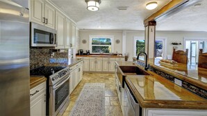 A kitchen with granite countertops, stainless steel appliances, and a large window. - Heated Pool Home Near Siesta Key Beach | 3BR | Walk to Dining | Pet Friendly (Sarasota)