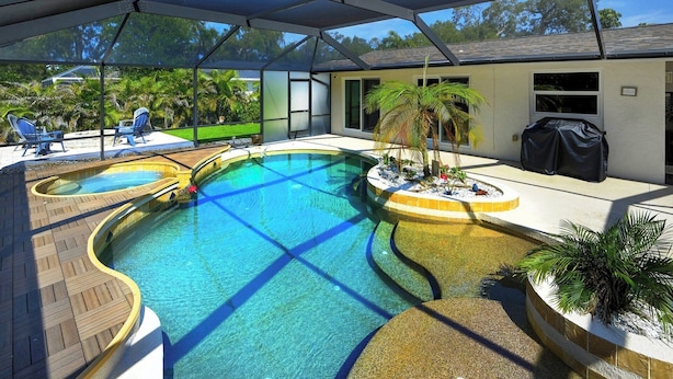 A swimming pool with a sunshade, lounge chairs, and a patio area with plants. - Heated Pool Home Near Siesta Key Beach | 3BR | Walk to Dining | Pet Friendly (Sarasota)
