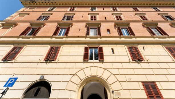 Un immeuble à plusieurs étages, de style architectural classique, caractérisé par des fenêtres en arc et une entrée centrale.