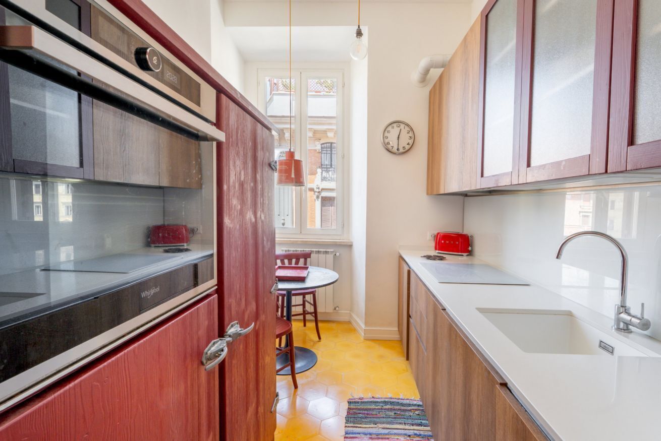 Una cocina compacta con refrigerador integrado, un lavamanos y una zona de comedor con mesa y sillas.