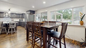 A modern kitchen with wooden cabinets, a dining table, and chairs. - House right on the lake w/ hot tub, kayak, SUP & games - great location (Shelton)