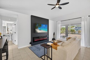 A modern living room with a flat-screen TV, a fireplace, a ceiling fan, and a view of the outdoors. - SW Florida, Professional, Minimalist, Comfy, Pet Friendly, Near Beaches! (North Port)