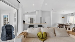 Una habitación de hotel moderna con una cama grande, una pequeña cocina y una mesa de comedor.