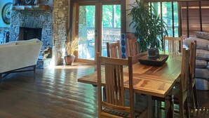 Een rustiek interieur met een stenen open haard, een houten eettafel en een kroonluchter.