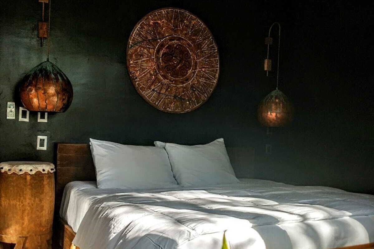 A bedroom with a bed, a hanging light fixture, and a wall-mounted decorative plate.