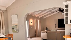 Un salón amplio con techo alto, una cocina con televisor integrado y un comedor con mesa y sillas.