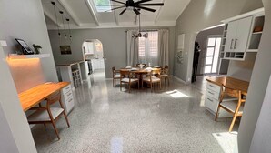 Una cocina amplia con comedor, muebles de cocina blancos y un ventilador de techo.