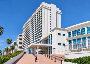 A modern hotel with a prominent entrance, multiple floors, and a clear sky.