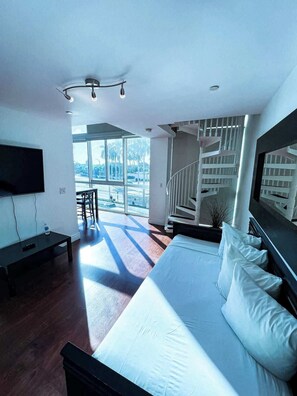 Ein modernes Schlafzimmer mit einem großen Bett, einem Fernseher und einer Treppe, die in einen Außenbereich führt.