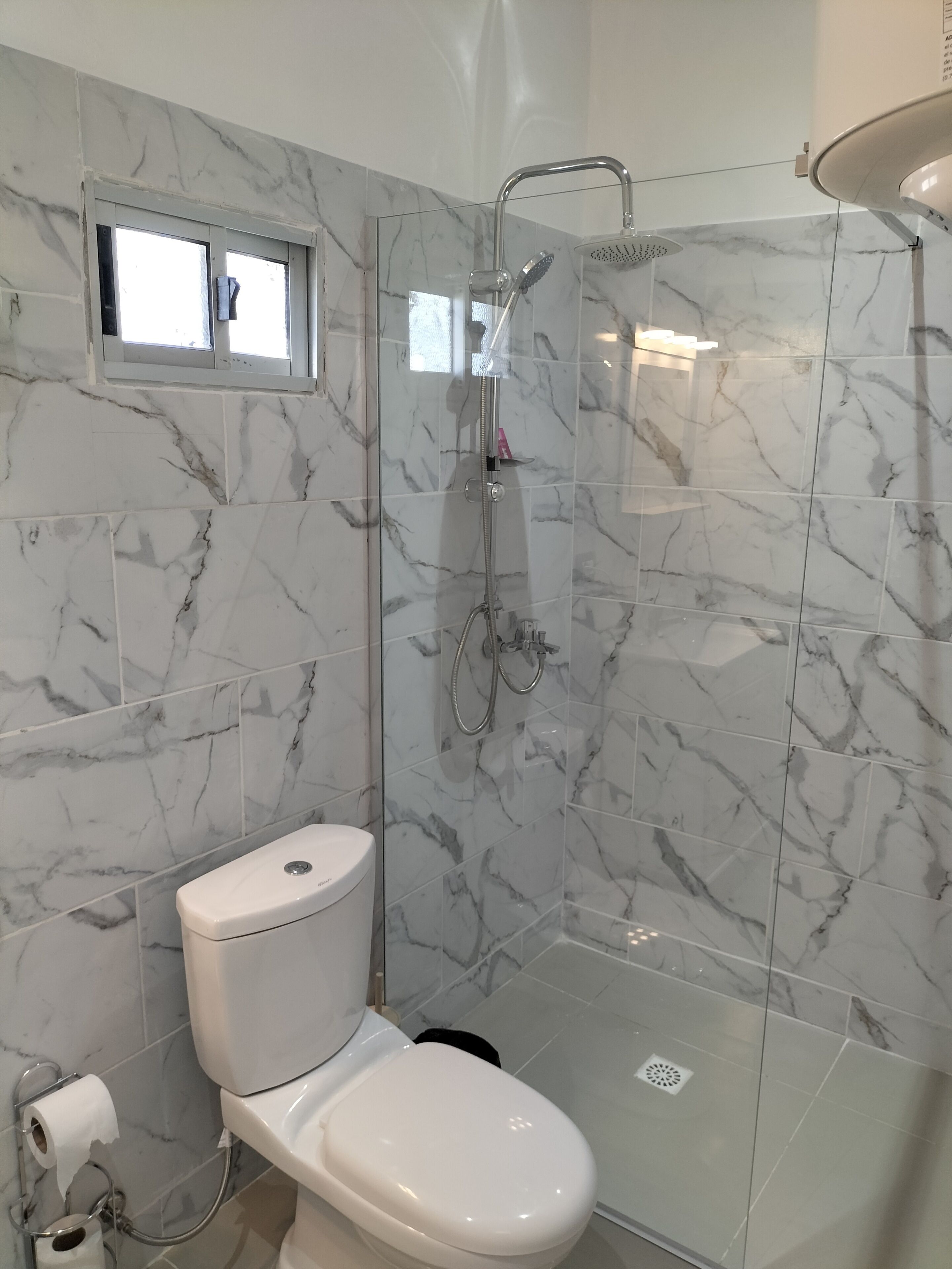 Un baño con inodoro, ducha y ventana.