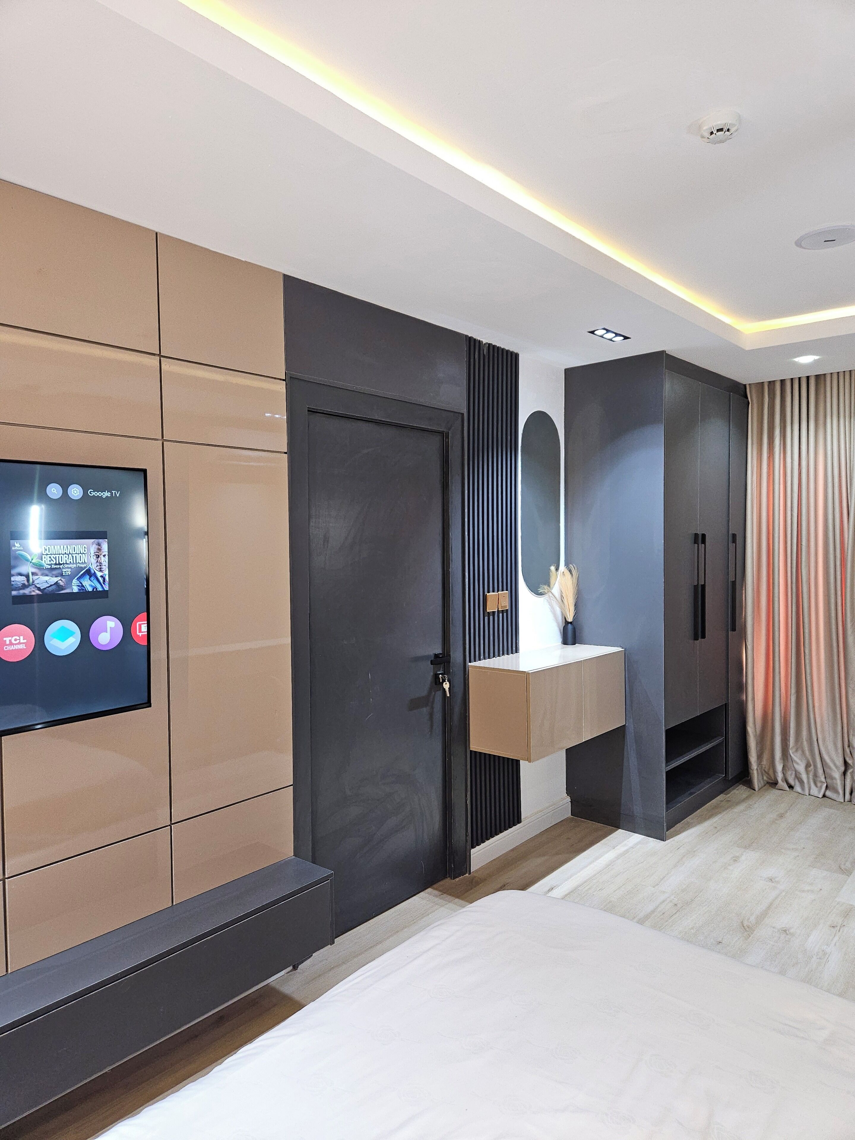 A modern bedroom with a TV mounted on the wall, a bedside table, a bed, and a wardrobe.