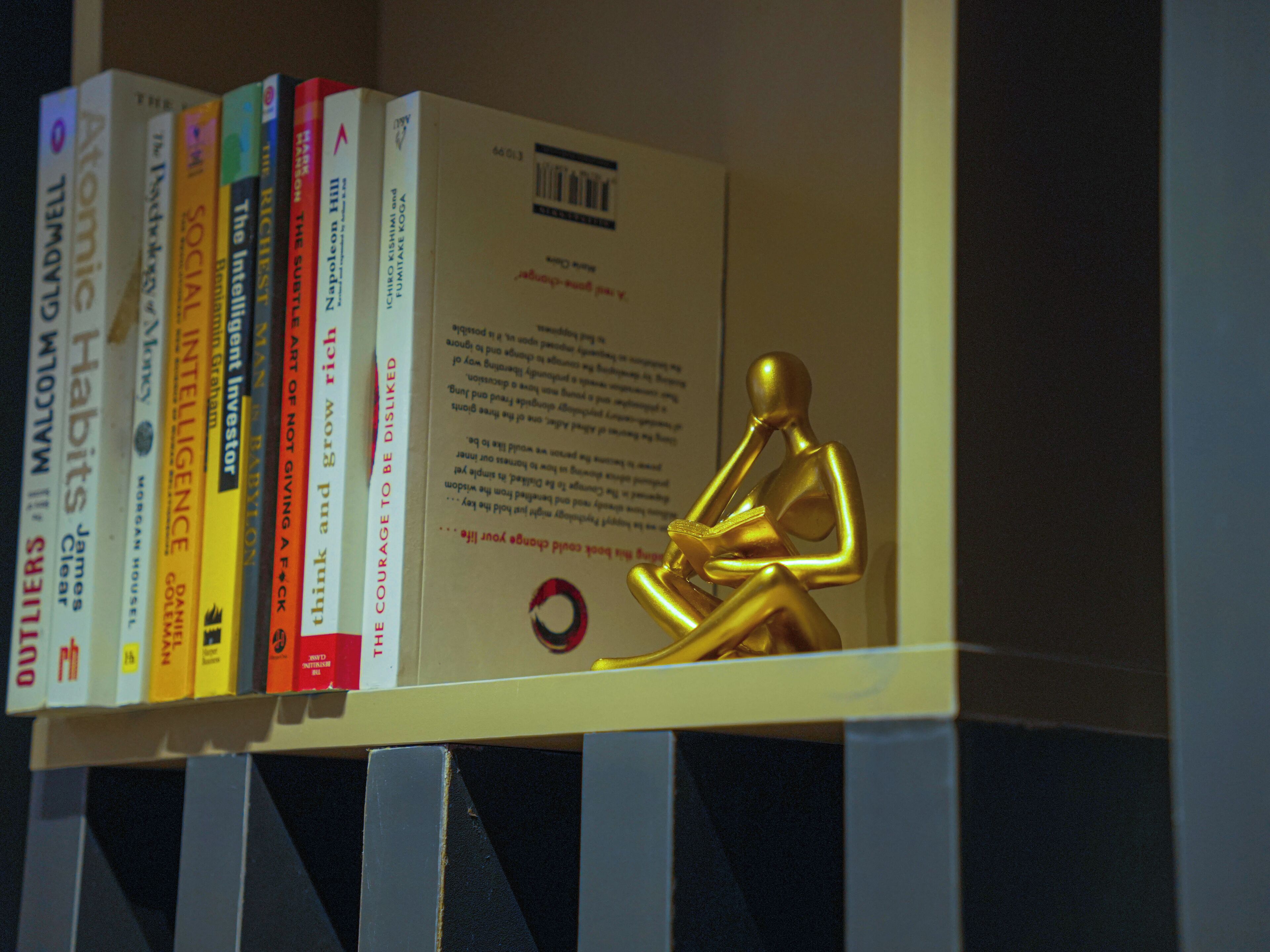A shelf with books and a golden statue.