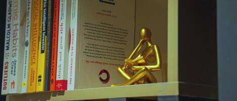 A shelf with books and a golden statue.
