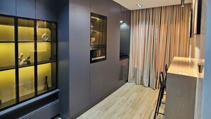 A modern kitchen with dark cabinetry, a built-in microwave, and a glass-fronted display cabinet. - Sapphire Suite (Abuja)