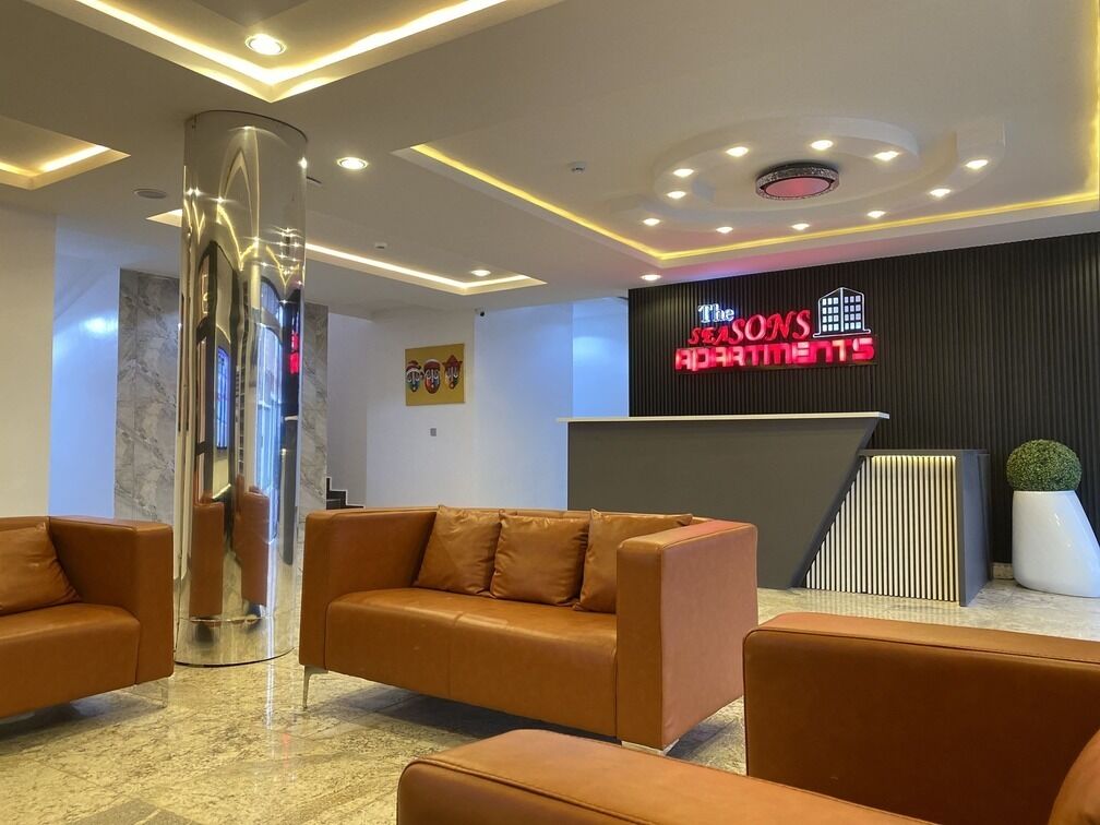 Un área de recepción con diseño moderno, que incluye un mostrador de recepción, sofás de cuero y un pilar decorativo.
