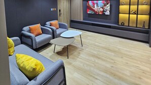 A modern living room with grey sofas, a white coffee table, and a flat-screen TV mounted on the wall. - Sapphire Suite (Abuja)