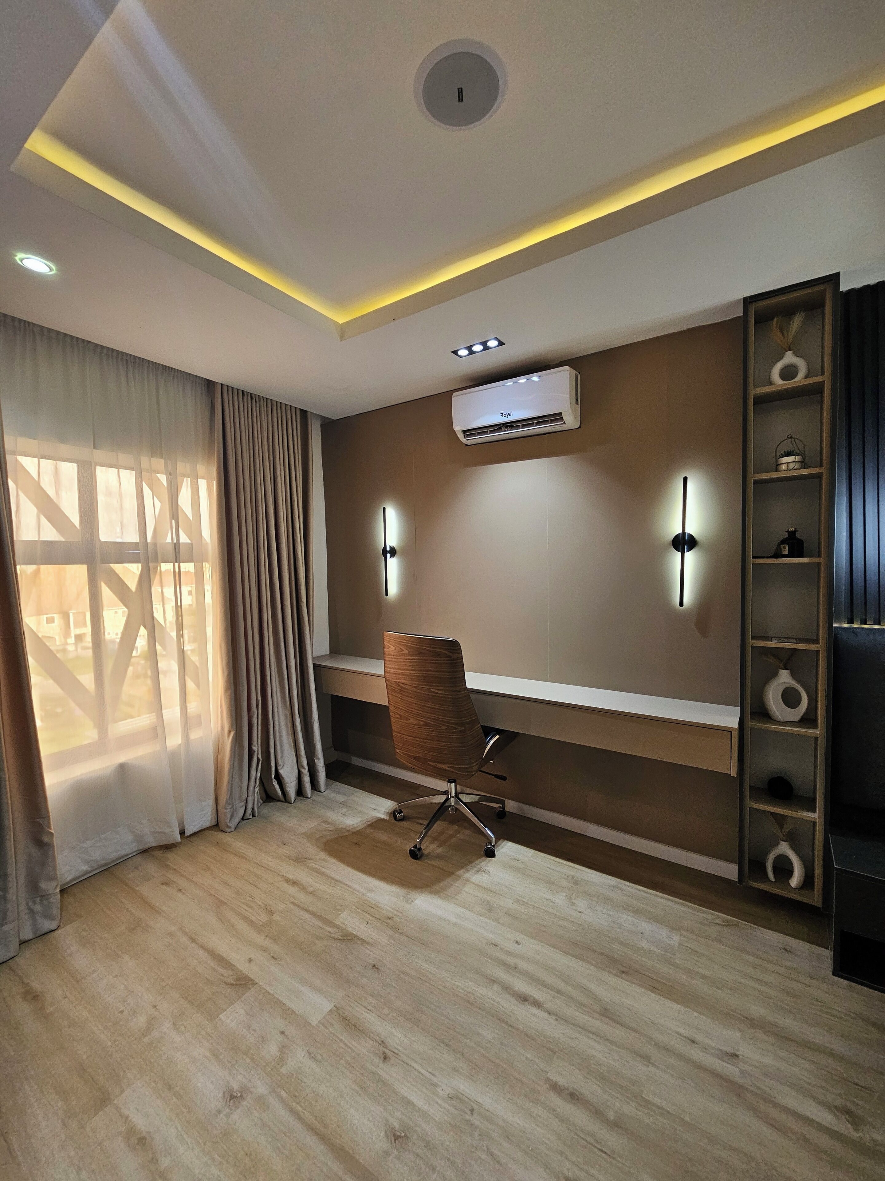 A modern office space with a desk, chair, and built-in shelving.