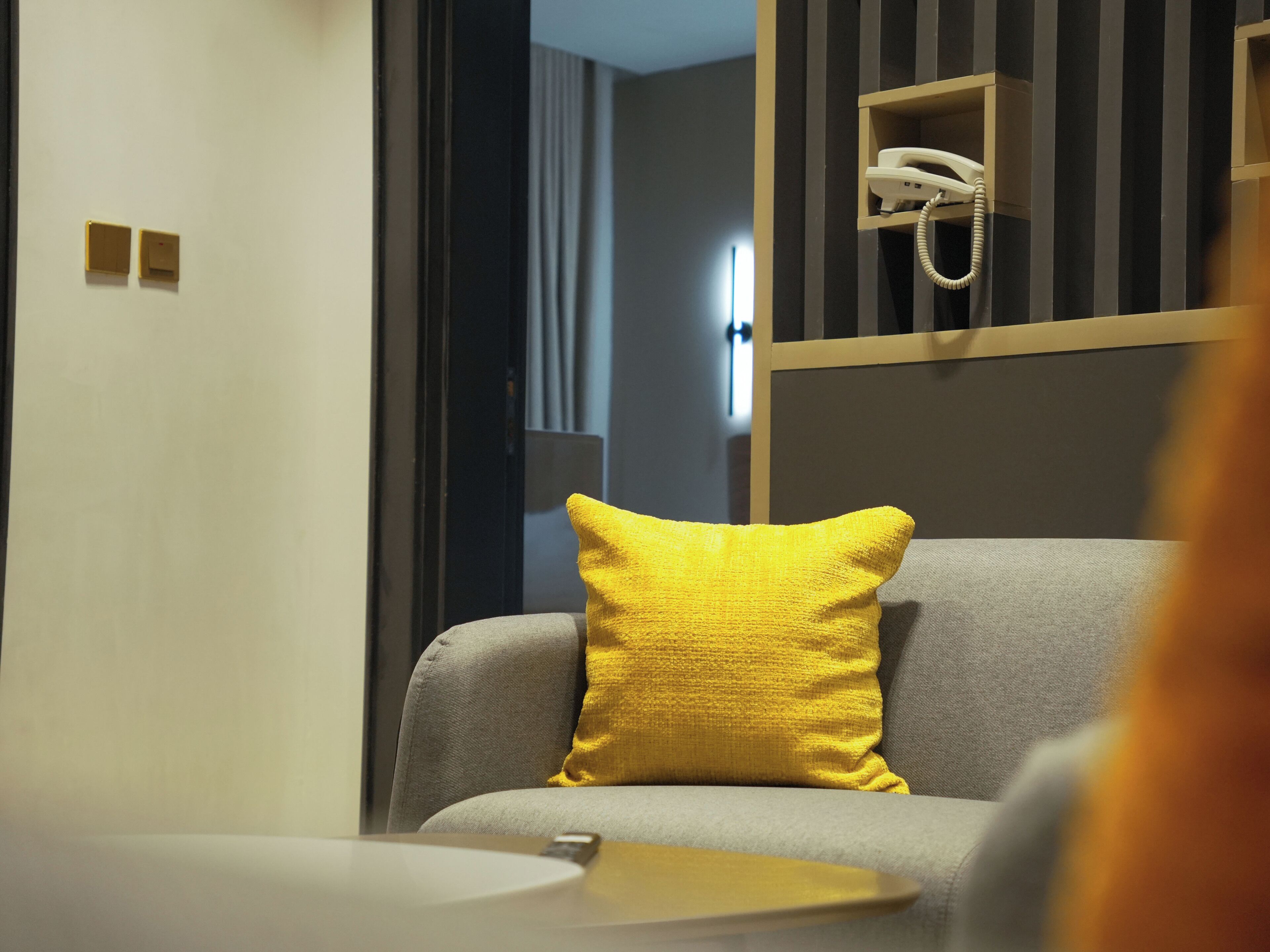 A modern living room with a grey sofa, a yellow pillow, and a small table.