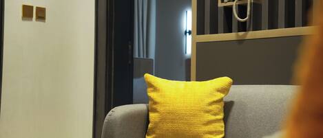 A modern living room with a grey sofa, a yellow pillow, and a small table.