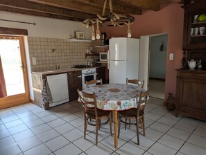 Uma cozinha com mesa de jantar, cadeiras, geladeira, micro-ondas e pia.