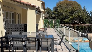 Área à beira da piscina com mobiliário de exterior e escadaria que dá acesso a uma piscina.
