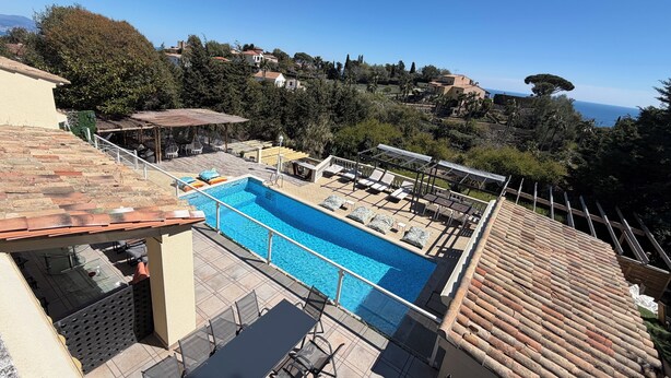 Una piscina en la azotea con vistas despejadas al mar, rodeada de árboles y edificios.