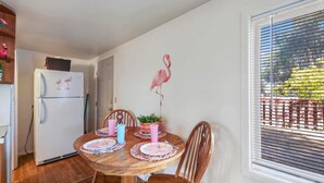 Un comedor con una mesa de madera, sillas y un refrigerador decorado con flamencos.