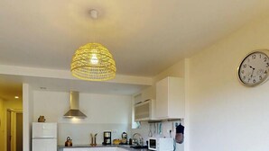 Una cocina moderna con armarios blancos, una campana extractora de acero inoxidable y una lámpara colgante.