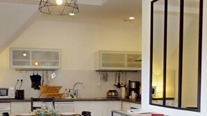 Una cocina moderna con armarios blancos, un microondas y un comedor con mesa y sillas.