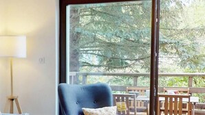 Una habitación con sofá, lámpara y vistas a un balcón con mobiliario exterior.