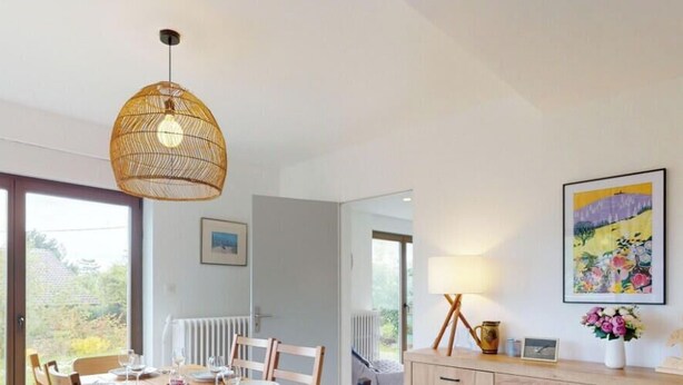 Una habitación moderna con un gran ventanal, una mesa de comedor, una silla, una lámpara colgante y un cuadro en la pared.