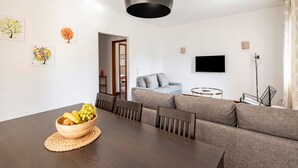Ein modernes Wohnzimmer mit Esstisch, Sofa und einem an der Wand montierten Fernseher.