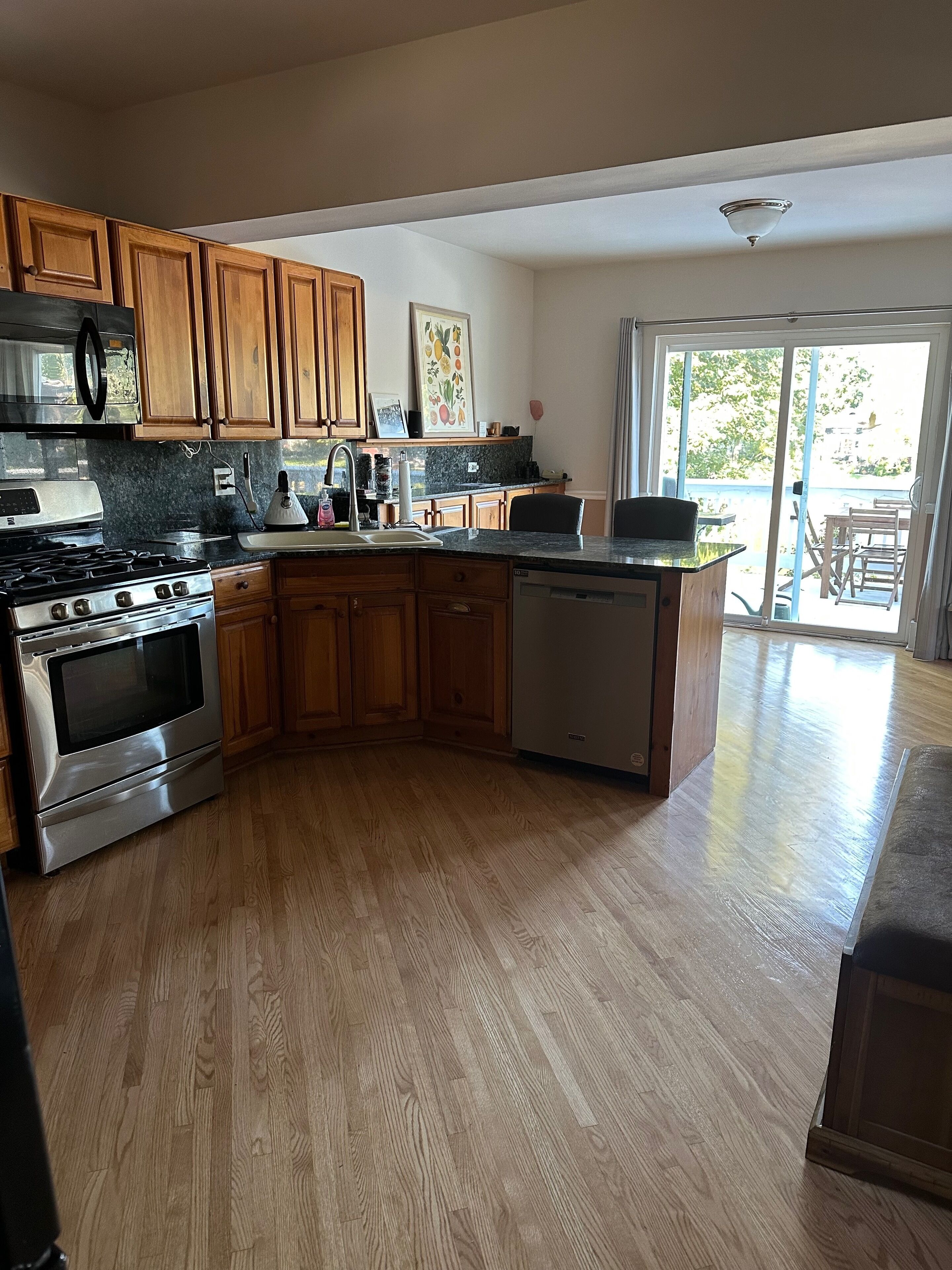 A kitchen with wooden cabinets, a stainless steel stove, a dishwasher, and a large window.