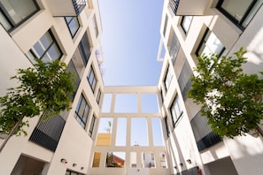 A modern building with a central atrium, large windows, and symmetrical design. - Luxury 3 rooms Apt• Balcony• Parking | HaKerem A25 (Tel Aviv)
