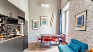 Een moderne keuken met grijze kastjes, een eethoek met oranje stoelen en een blauwe bank.