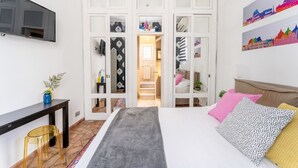 Een slaapkamer met een bed, nachtkastje en een aan de muur bevestigde televisie.