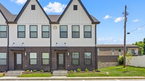 A modern townhouse with a symmetrical facade, two visible entry doors, and a small front yard with steps leading to the entrance.